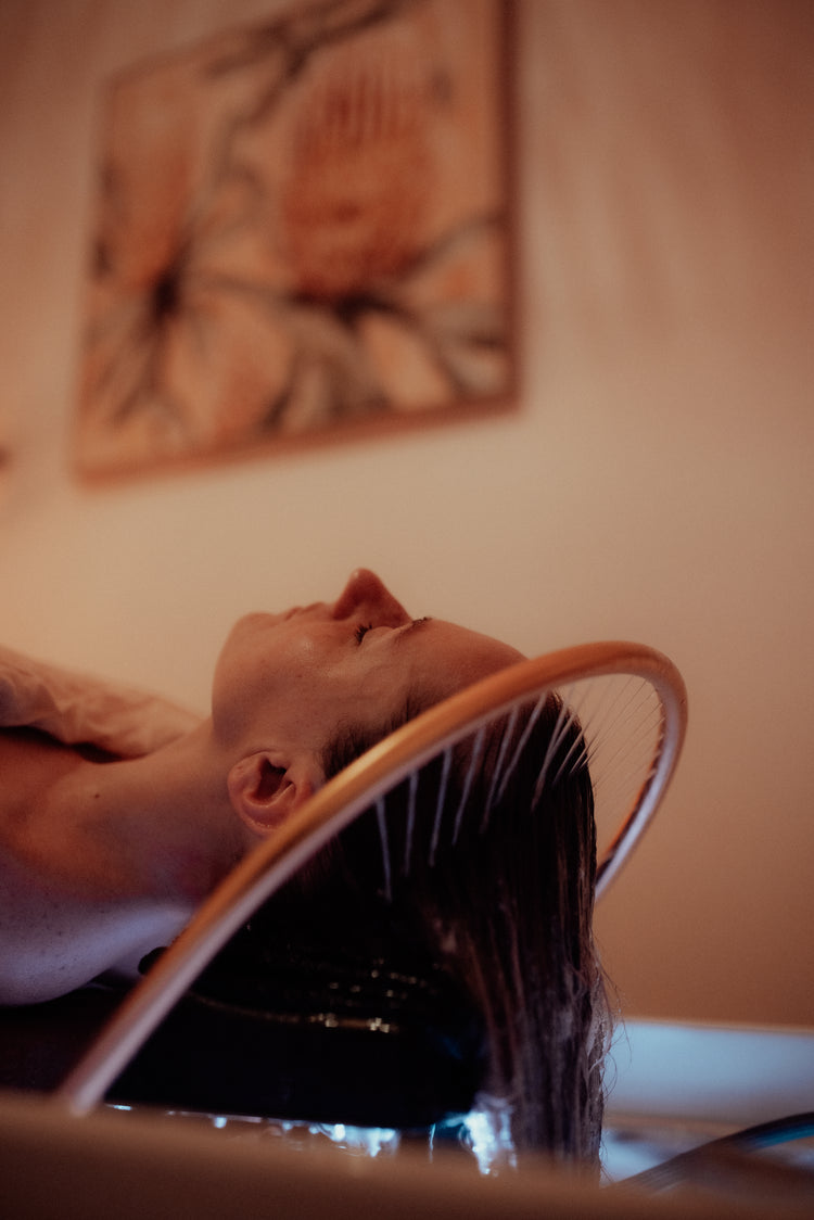 Client relaxing with scalp tools, Kansa wand, and essential oils in a private Head Spa room